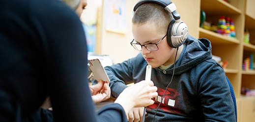 Student wearing headphones working with an adult