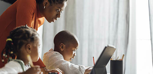 adult working with 2 students and a laptop