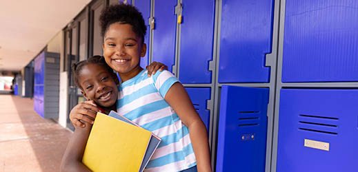 students next to lockers with arms around each other's shoulders