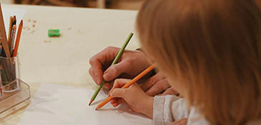 student drawing on paper with adult